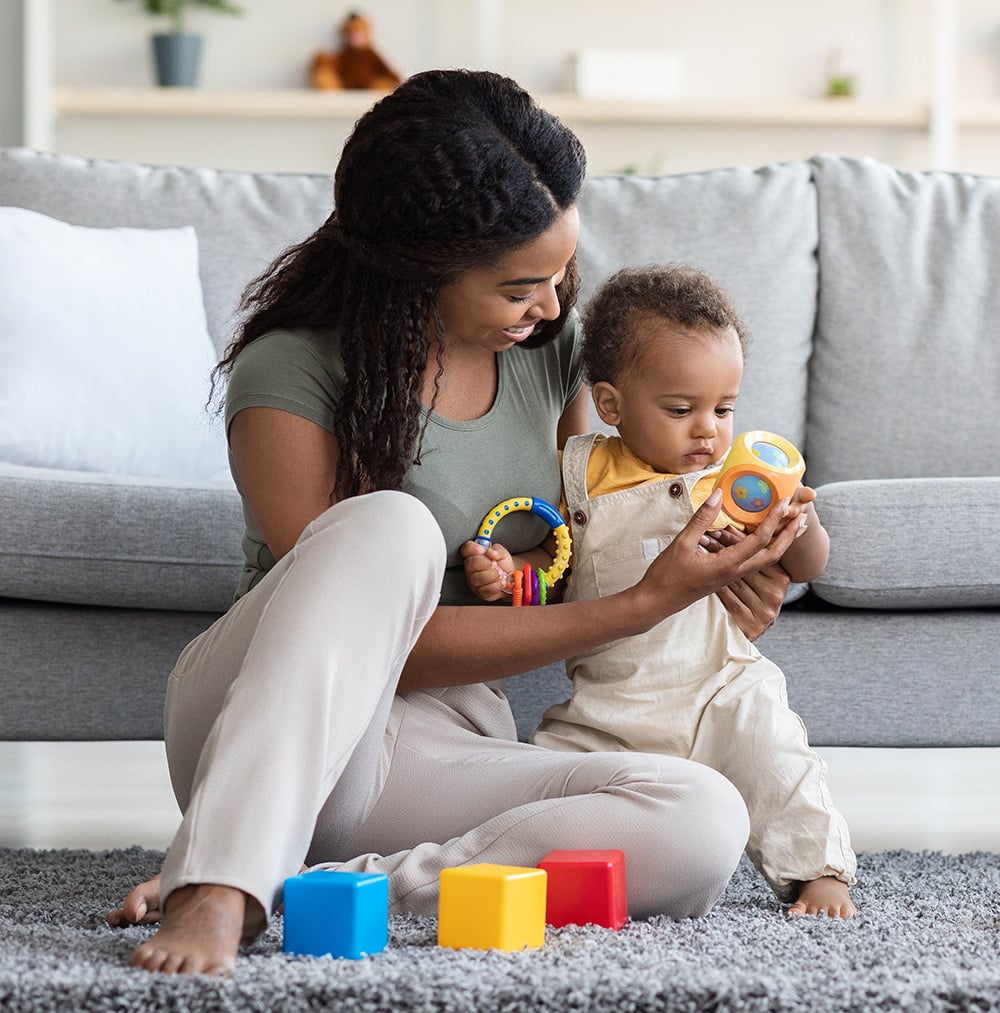 A caring mother playing with her toddler on a cozy living room floor, engaging with colorful toys to promote early development and bonding